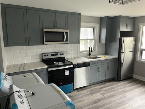 a remodeled kitchen with gray cabinets and black appliances and white counter tops